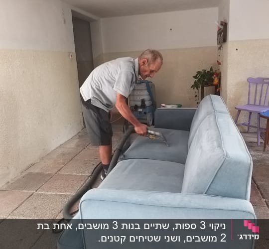 אדם מנקה ספה עם שואב אבק
